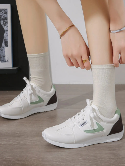 Green-accent white sneakers worn with cream socks