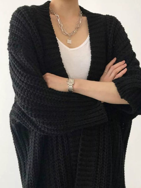Black chunky cardigan worn over a white top, close front view