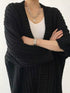 Black chunky cardigan worn over a white top, close front view