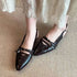 Pointed slingback flats worn at an angle to show the open heel and side cutout