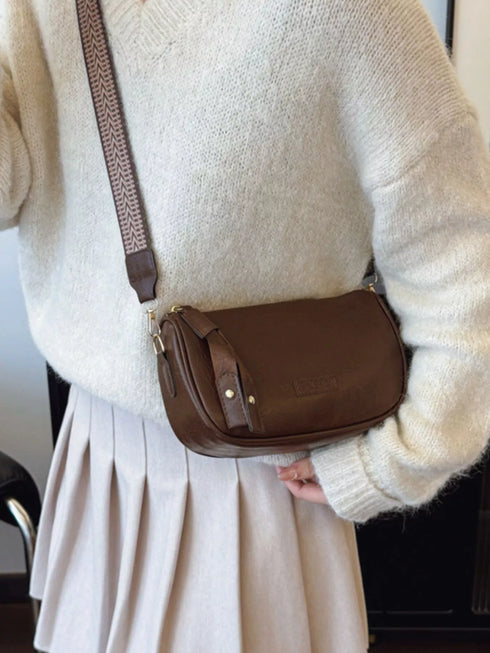 Coffee brown crossbody bag worn against a cream sweater