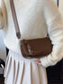Coffee brown crossbody bag worn against a cream sweater
