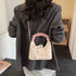 Cream crossbody purse hanging from its long strap over a blazer