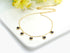 Gold-tone black heart charm necklace beside pale flowers on a white tray
