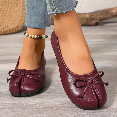 Burgundy bow-detail split-toe flats worn on a model, front view