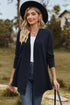 Dark blue long cardigan worn open with a hat and handbag