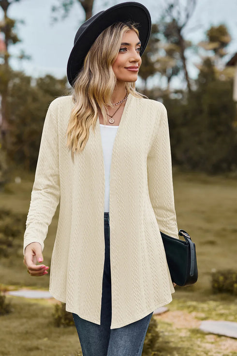 Angled view of cream textured cardigan with a black bag