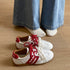 Pair of white sneakers with red side accents and gum-colored soles