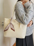 Beige woven faux leather tote shown hanging from a model's shoulder