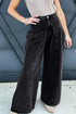 Black wide-leg jeans shown from the front with a hand on the waist