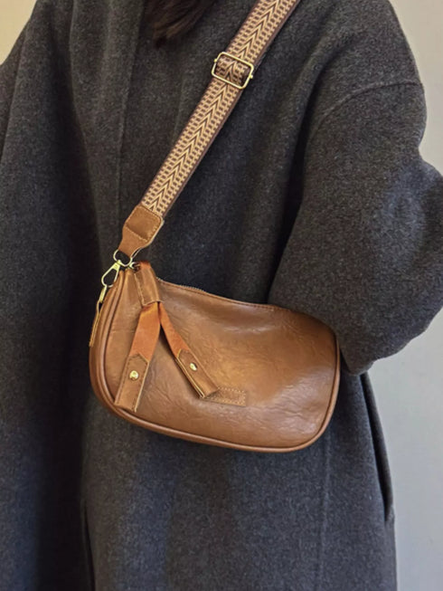Side view of brown crossbody bag and wide patterned strap