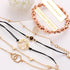 Rose-tone bracelet stack arranged with black cords and geometric charms