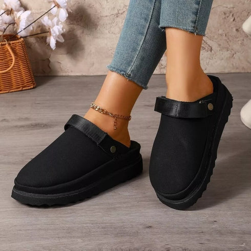 Black round-toe slip-on clogs worn on a model, angled front view