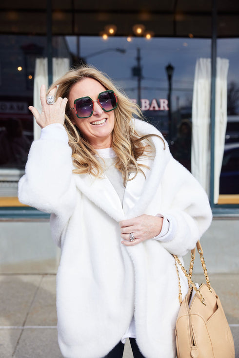 White Pretty Rugged hooded cardigan worn with sunglasses and a tan handbag