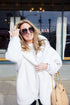 White Pretty Rugged hooded cardigan worn with sunglasses and a tan handbag