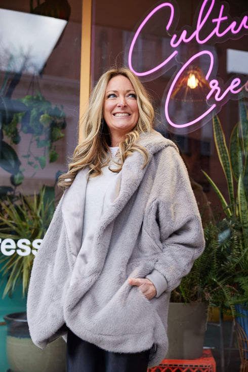 Grey Pretty Rugged plush cardigan styled with dark pants outside a storefront