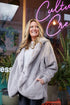 Grey Pretty Rugged plush cardigan styled with dark pants outside a storefront