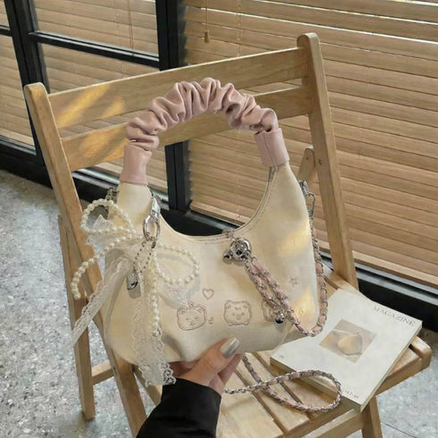 Cream mini purse displayed on a chair with bow and hanging accents
