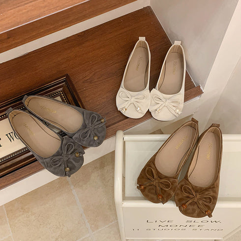Beige bow flats beside brown and gray pairs on steps