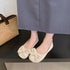 Beige round-toe bow flats worn with a blue-gray skirt