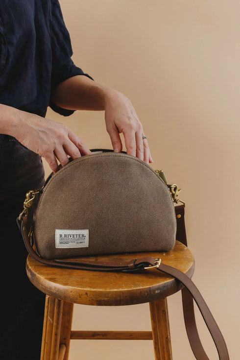 Hopper bag on a wooden stool with hands holding the opening