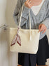 Front view of beige woven shoulder tote with a hand resting at the top