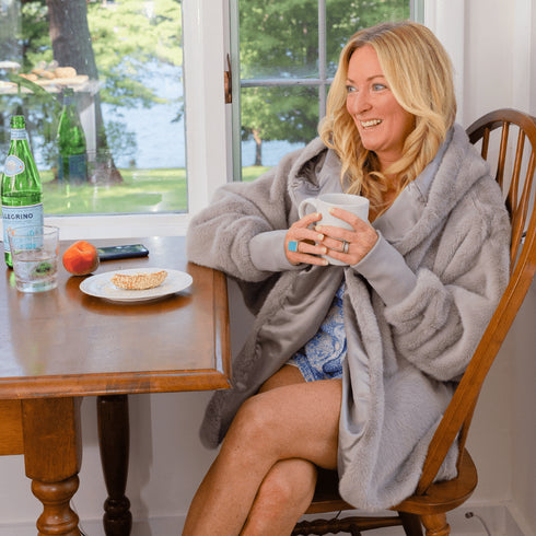 Grey Pretty Rugged hooded cardigan worn while seated at a table holding a mug