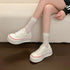 White retro platform sneakers worn while seated, showing rounded toes and red trim