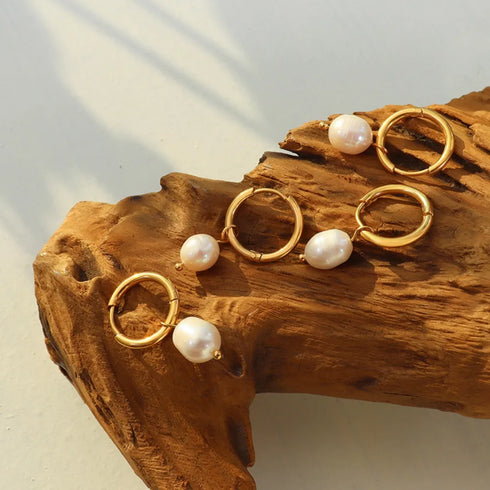 Gold-plated freshwater pearl hoops displayed on wood in angled light