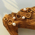 Gold-plated freshwater pearl hoops displayed on wood in angled light