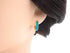 Turquoise enamel hoop earring shown on a display model
