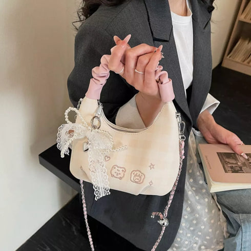 Cream mini purse carried by its pink ruched top handle