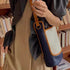 Side view of beige canvas and navy shoulder bag with brown adjustable strap