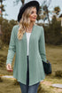 Angled front view of light green cardigan with a black bag