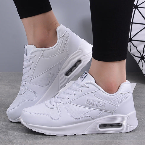 White platform sneakers worn with black leggings, showing side air-cushion detail