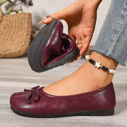 Burgundy split-toe flats with one shoe held to show its sole