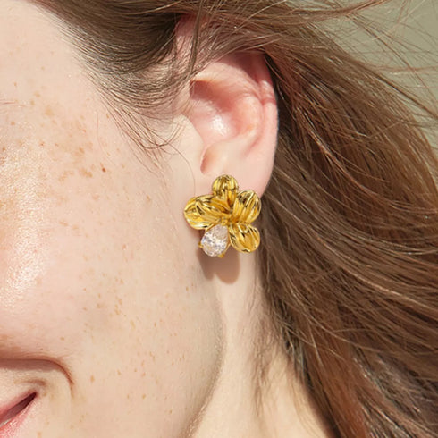 Gold-tone flower stud earring worn on an ear