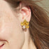 Gold-tone flower stud earring worn on an ear