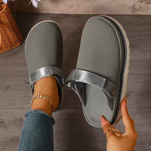 Top view of gray clogs with one shoe worn and the other held