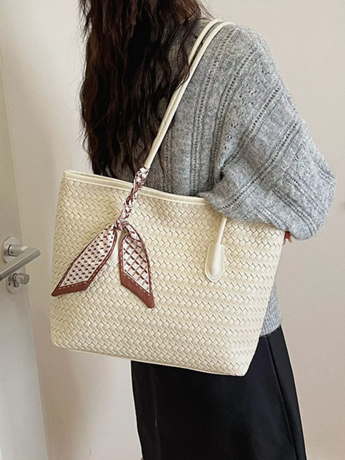Rear angled view of beige woven tote with scarf tied to a handle