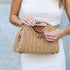 Close-up of clasp and top handle on khaki woven straw bag