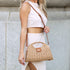 Khaki Stella woven straw bag worn with its crossbody strap