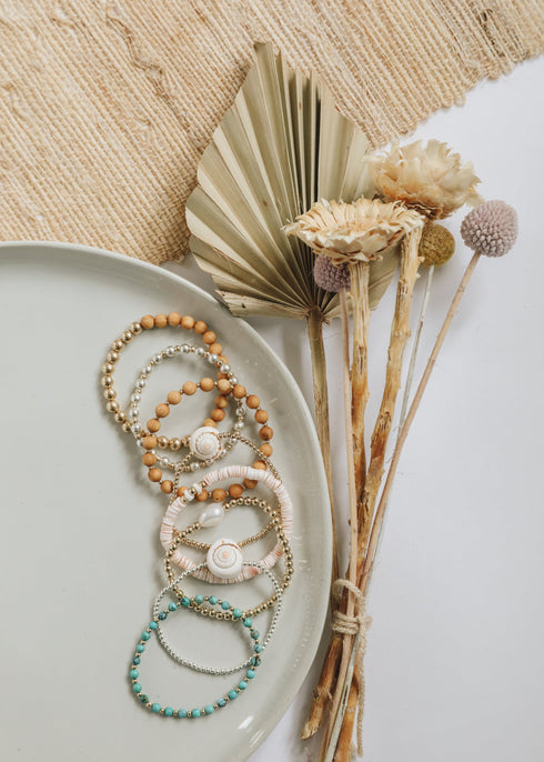 Conch-shell and gold-filled beaded jewelry arranged with coordinating bracelets