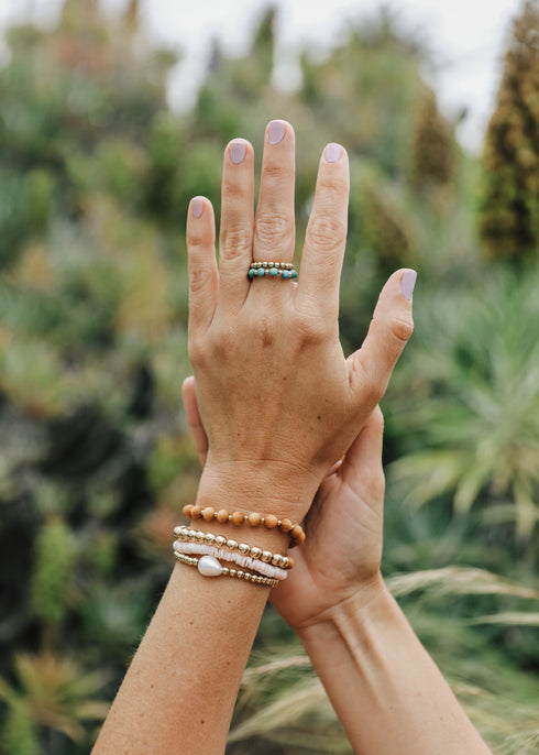 Conch-shell gold-filled bracelet worn in a layered wrist stack