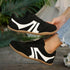 Side profile of black retro sneakers with tan-colored soles