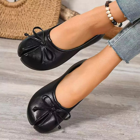 Angled view of black bow-detail flats showing split toes