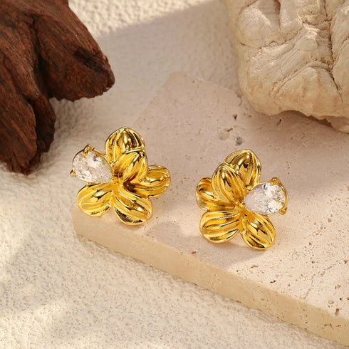 Gold-plated floral studs displayed on a pale stone block