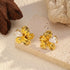 Gold-plated floral studs displayed on a pale stone block