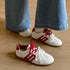 White-and-red low-top sneakers worn with wide-leg jeans, angled view