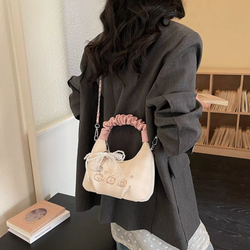 Side-back styling view of cream mini crossbody with pink handle